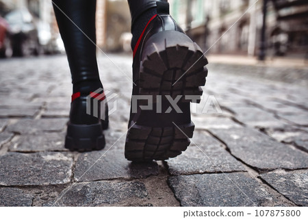 Close up of woman legs in black shous walking on the street in the city. Close up of woman legs in black shous walking on the street in the city. 107875800