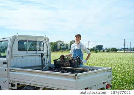 A man loading agricultural products onto the back of a light truck 107877091