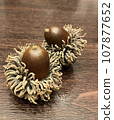 two large acorns placed on a wooden table 107877652