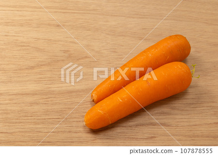 Two carrots placed on a wooden board "left empty" 107878555