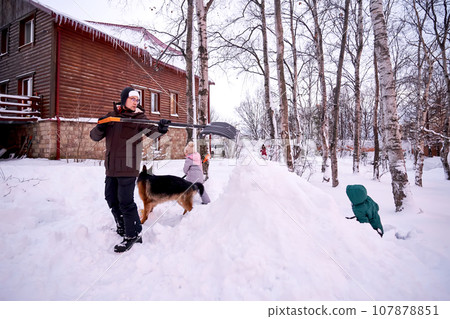 A family builds a slide in the yard in winter. A family builds a slide in the yard in winter. 107878851