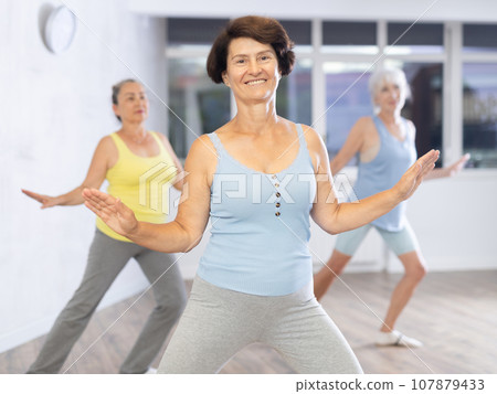 Happy mature woman practicing dance positions during workout session Happy mature woman practicing dance positions during workout session 107879433
