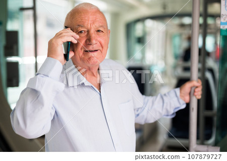 Senior European man having telephone conversation in tram Senior European man having telephone conversation in tram 107879727