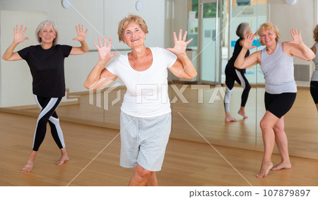 Cheerful senior woman enjoying active dancing in dance studio Cheerful senior woman enjoying active dancing in dance studio 107879897