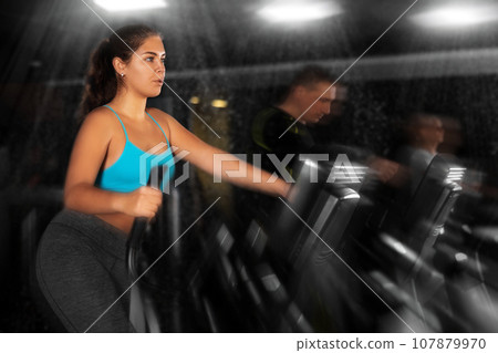 Fitness woman in sportswear doing cardio training on ellipsoid in gym Fitness woman in sportswear doing cardio training on ellipsoid in gym 107879970
