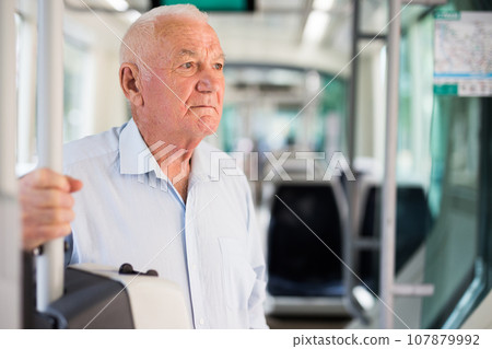 Elderly man standing in tram 107879992
