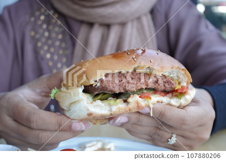 hand holding beef burger on table close up hand holding beef burger on table close up 107880206
