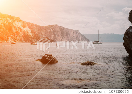 calm azure sea and volcanic rocky shores. Small waves on water surface in motion blur. Nature summer ocean sea beach background. Nobody. Holiday, vacation and travel concept calm azure sea and volcanic rocky shores. Small waves on water surface in motion blur. Nature summer ocean sea beach background. Nobody. Holiday, vacation and travel concept 107880655