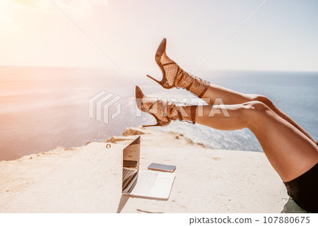 Woman sea laptop. Business woman in yellow hat freelancer with laptop working over blue sea beach. Girl relieves stress from work. Freelance, digital nomad, travel and holidays concept 107880675