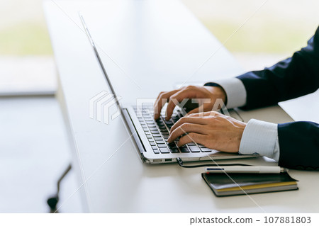 一個穿著西裝的男人的手在筆記型電腦上打字 107881803