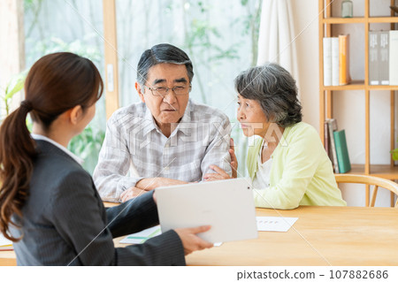Senior couple discussing their concerns with a consultant Senior couple discussing their concerns with a consultant 107882686