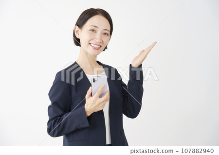 手持智能手機並用手掌白色背景指向右側的女商人 107882940