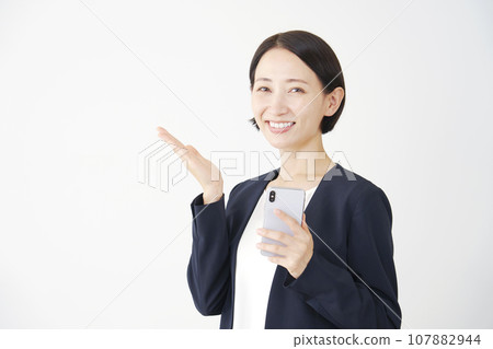 手持智能手機並用手掌白色背景指向左側的女商人 107882944