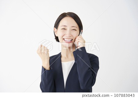 Business woman doing a fist pump while calling on a smartphone, white background 107883043