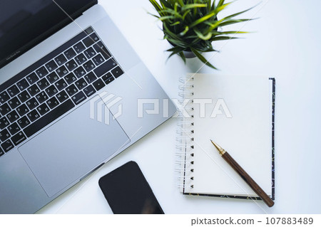 open notepad with blank sheet for resolutions or to do list. Laptop and smartphone on background 107883489