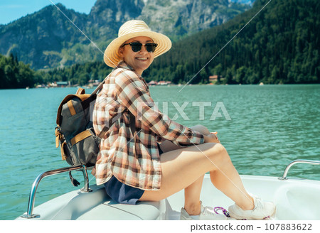 woman with backpack sitting on deck of paddleboat sailing in Blue mountain lake 107883622