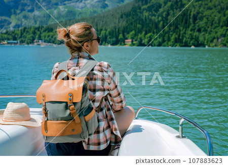 traveller woman enjoying beautiful view of turquois Lake and mountains sitting on sailing paddleboat traveller woman enjoying beautiful view of turquois Lake and mountains sitting on sailing paddleboat 107883623