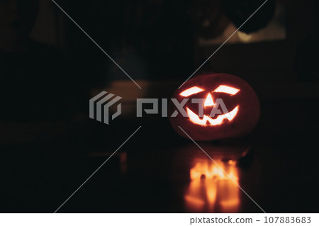 jack-o-lantern glowing in darkness. Candle flame in traditional halloween pumpkeen. jack-o-lantern glowing in darkness. Candle flame in traditional halloween pumpkeen. 107883683