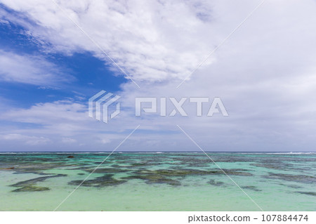 Calm ocean water is under blue sky with clouds 107884474