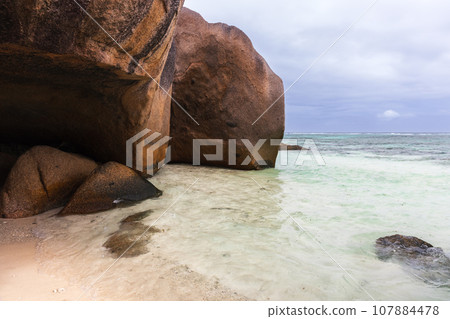 Dark rocks on the coast of La Digue island, Seychelles. Anse Union Dark rocks on the coast of La Digue island, Seychelles. Anse Union 107884478