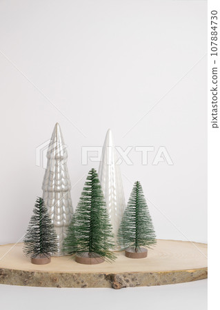 Modern Christmas trees. Decorative Beige, White and Green Christmas Decoration on a Wooden Stand with a Gray background. Nordic Festive Decor. Boho, Scandinavian Style Design Trendy Minimal Ornament. 107884730