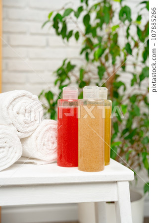 Rolled towels and shower gels on shelf in a bathroom 107885266