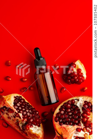 Cosmetic serum dropper bottle with pomegranate flavor on red background 107885402