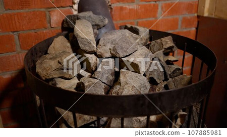 Stones in the oven to produce steam and heat in the steam room. Close-up of stones in the steam room. Hot stones in the sauna close-up. Stones in the oven to produce steam and heat in the steam room. Close-up of stones in the steam room. Hot stones in the sauna close-up. 107885981