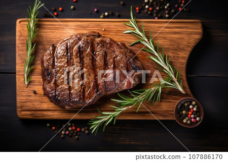 Grilled meat barbecue steak on wooden cutting board with rosemary and copy space. Top view. 107886170