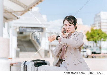 Business woman/young woman calling on smartphone while checking her watch Business woman/young woman calling on smartphone while checking her watch 107886533