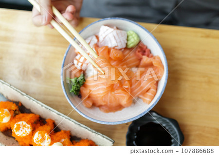 Asian woman eating salmon slice sashimi with rice in Japanese restaurant 107886688