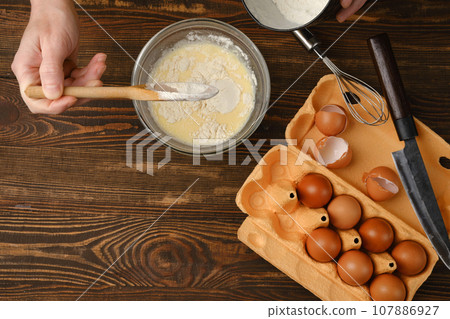 Top view of unrecognizable man adding flour to mixed eggs Top view of unrecognizable man adding flour to mixed eggs 107886927