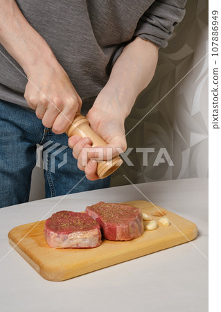 Sprinkle steak with salt from hand grinder Sprinkle steak with salt from hand grinder 107886949