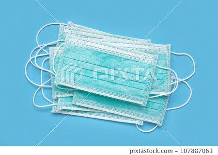 Surgical face mask on blue background protection against COVID-19 coronavirus. Healthcare and medical concept Surgical face mask on blue background protection against COVID-19 coronavirus. Healthcare and medical concept 107887061