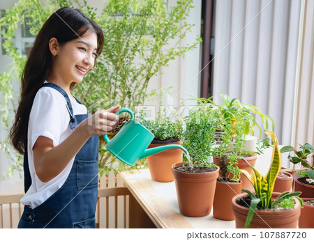 AI-generated image of a woman watering houseplants on her balcony 107887720