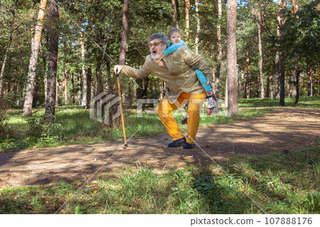 Grandfather walks with his granddaughter in the park. 107888176
