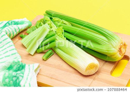 Fresh Celery Stem and Chopped Celery Sticks on Wooden Cutting Board 107888464