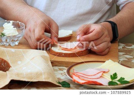 Cook's hand decorates the bread and butter with ham Cook's hand decorates the bread and butter with ham 107889925