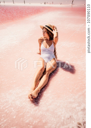 Woman pink salt lake. She lies in a white bathing suit. Wanderlust photo for memory 107890110