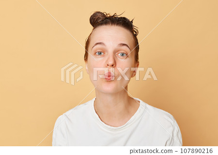 Positive funny woman washes hair applies shampoo taking shower isolated over beige background posing with purse lips having fun while doing hygiene procedures in bathroom. 107890216