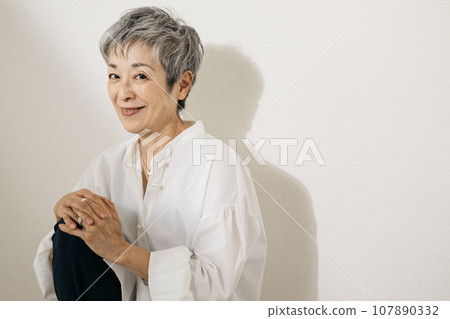 頭髮花白、穿著白襯衫、盤膝坐的優雅日本女子。 107890332