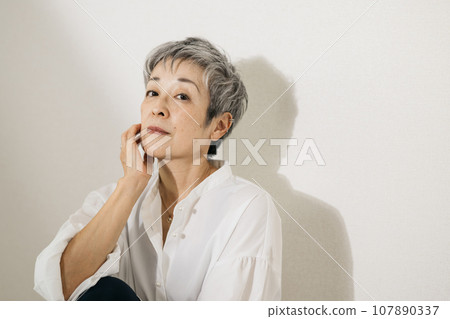 頭髮花白、穿著白襯衫、盤膝坐的優雅日本女子。 107890337