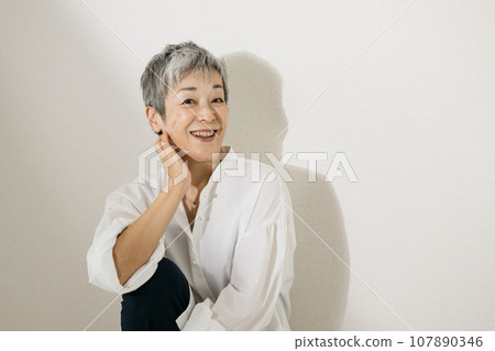 頭髮花白、穿著白襯衫、盤膝坐的優雅日本女子。 107890346