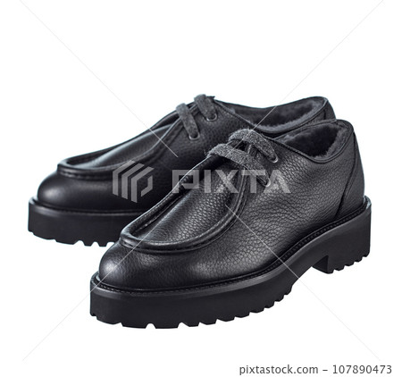 Stunning pair of men's derby boots made of thick black leather, with lacing, insulated with natural fur, on a high powerful, isolated on a white background. 107890473