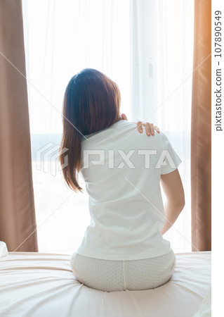 Woman having Shoulder and Neck pain during sitting on bed at home. Muscle painful due to Myofascial pain syndrome and Fibromyalgia, rheumatism, Scapular pain, Cervical Spine. Waking and Health concept 107890549