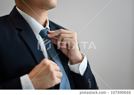 Close up of a businessman in formal clothes adjusting his necktie on white background 107890688