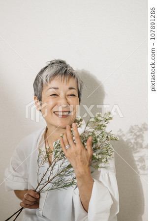 優雅的日本女人,頭髮灰白,手捧鮮花 優雅的日本女人,頭髮灰白,手捧鮮花 107891286