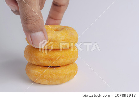 Hand with Donuts cake bakery sprinkled with sugar on white 107891918