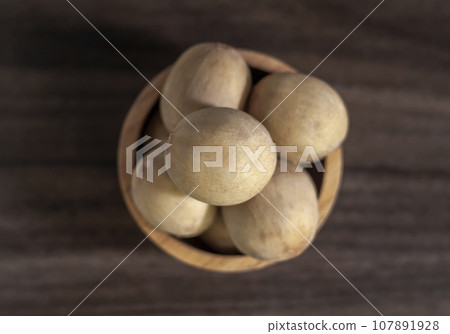 Langsat, Longkong, placed in a wooden cup set on a wooden board table dark blurred background Langsat, Longkong, placed in a wooden cup set on a wooden board table dark blurred background 107891928