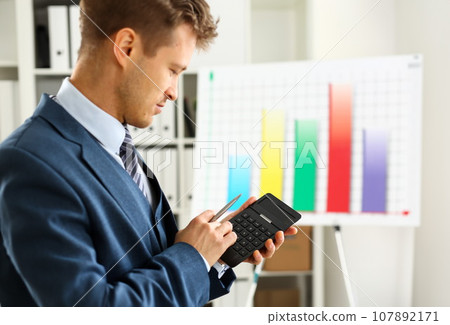 Male arm in suit hold calculator pressing buttons Male arm in suit hold calculator pressing buttons 107892171